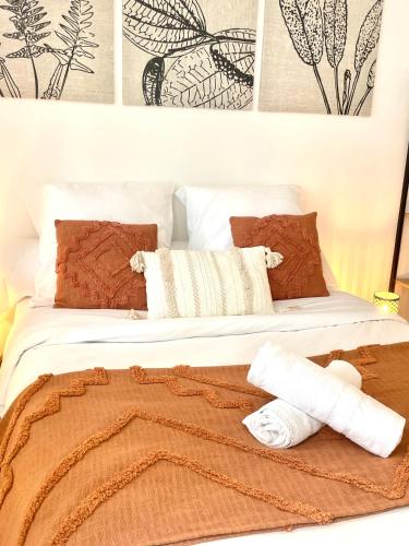 ein Bett mit einer braunen Decke und Kissen darauf in der Unterkunft Appartement Vincennes proche métro 15 minutes Marais in Vincennes