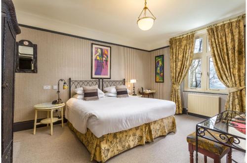 a bedroom with a large white bed and a window at Orestone Manor in Torquay