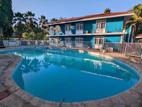 a swimming pool in front of a blue house at Gallivanters Hostel in Dar es Salaam