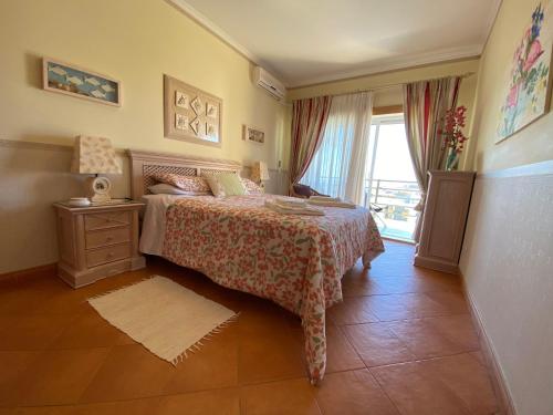 een slaapkamer met een bed met een tafel en een raam bij Condomínio do Mar in Lagos