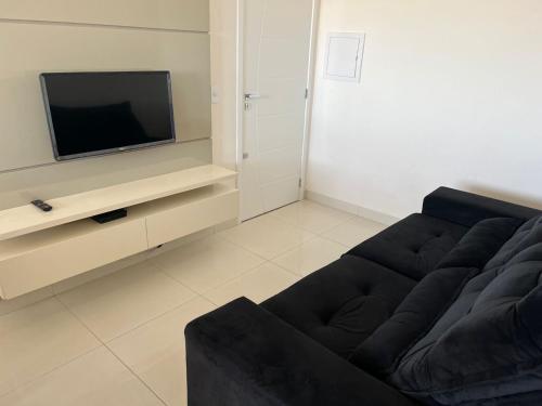 sala de estar con sofá negro y TV en Conceito Saúde, Orthomed, Cot, UMC, VEM PRA CA!, en Uberlândia