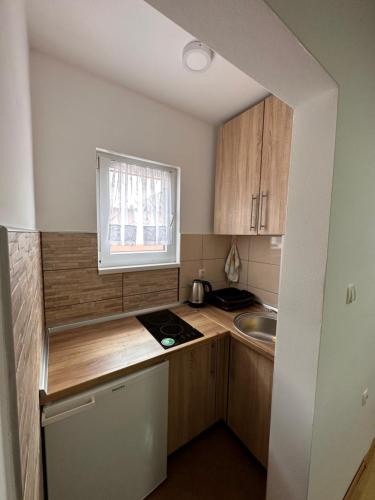 a small kitchen with wooden cabinets and a sink at Stan Zenica in Zenica
