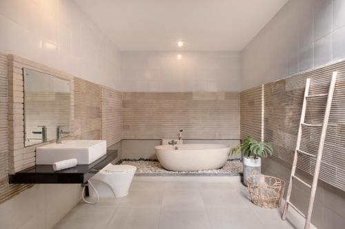 a bathroom with a tub and a toilet and a sink at Villa Lapiz Lazuli Seminyak Kuta in Seminyak