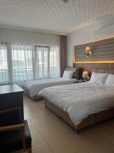 a hotel room with two beds and two windows at Hotel Stella in Kuşadası