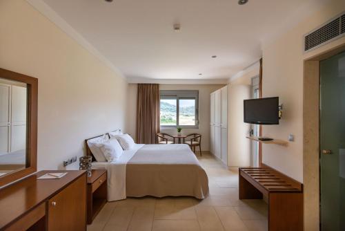 a hotel room with a bed and a television at Almiriki Chios Rooms & Apartments in Líthion