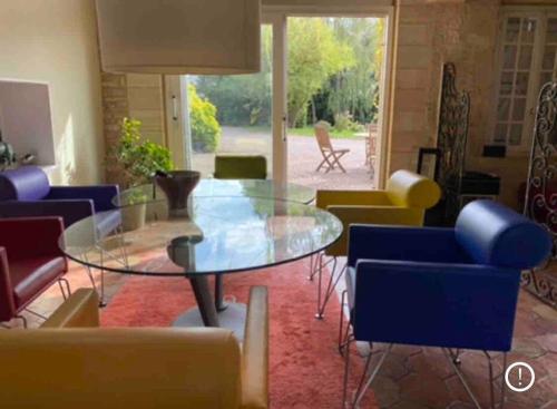 a living room with a glass table and chairs at Propriété à 3 mins du Château du Haras du Pin in Le Pin-au-Haras