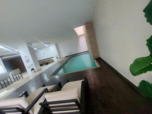 una piscina en una habitación con sillas y mesa en ZAFIRO SUITE CON VISTA CIUDAD/PISCINA/GYM/ PARQUEO, en Guayaquil