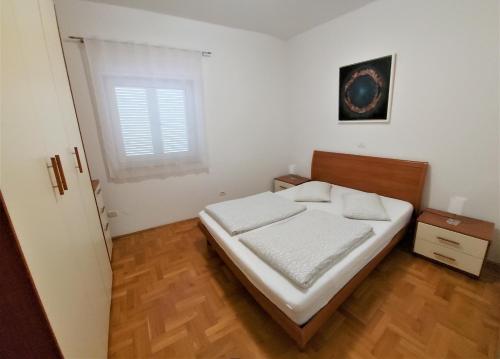 een slaapkamer met een bed met witte lakens en een raam bij Apartments Aurora near beach in Medulin