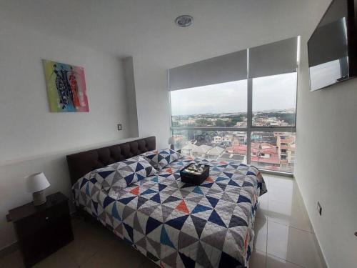 1 dormitorio con cama y ventana grande en ZAFIRO SUITE CON VISTA CIUDAD/PISCINA/GYM/ PARQUEO, en Guayaquil