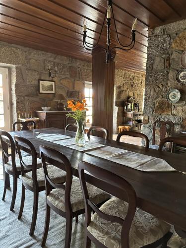 a large wooden table with chairs and a vase of flowers at Casa dos três rapazes in Monte Córdova