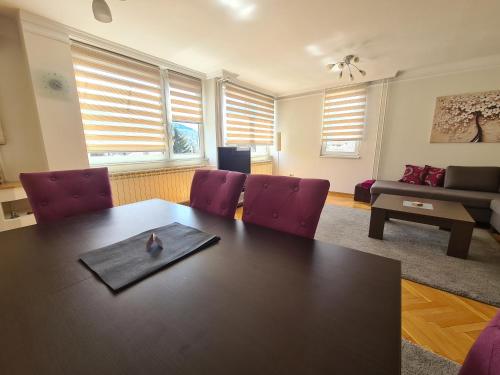 ein Wohnzimmer mit einem Tisch und lila Stühlen in der Unterkunft Walnut Apartment - Private Garage in Sarajevo