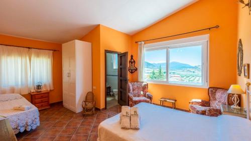 1 dormitorio con paredes de color naranja, 1 cama y ventana en La Martinica Teba by Ruralidays en Teba