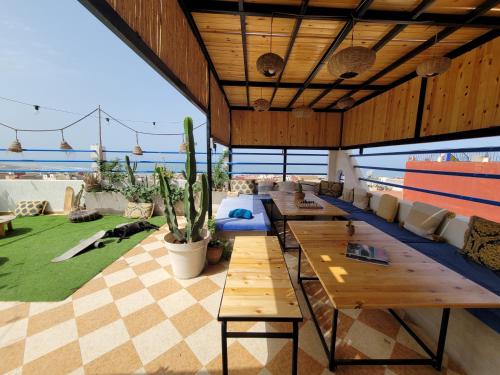 un patio con mesas y sofás y vistas al océano. en Good Wave Surf House, en Tamraght Ou Fella