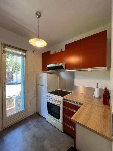 une cuisine avec des armoires marron et un four blanc dans l'établissement 4PA76 Appartement avec piscine et parking, à Collioure