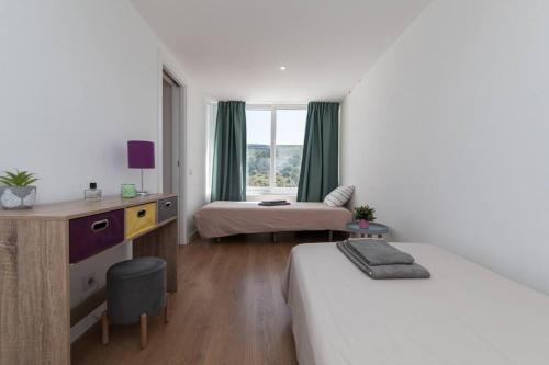 セジンブラにあるCasa das Andorinhas - T2 renovado com terraçoのベッド2台と机と窓のある寝室