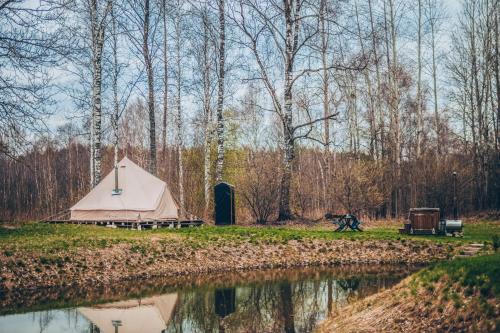 una tenda accanto a un bacino d'acqua con alberi di Glamping in - luxury tent 