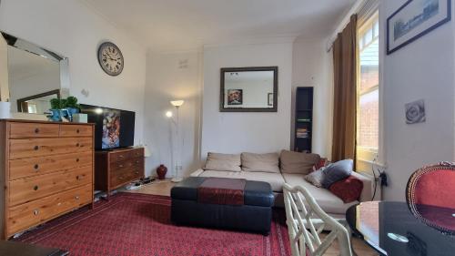 a living room with a couch and a dresser at Extra Large One Bedroom Flat with Parking in London
