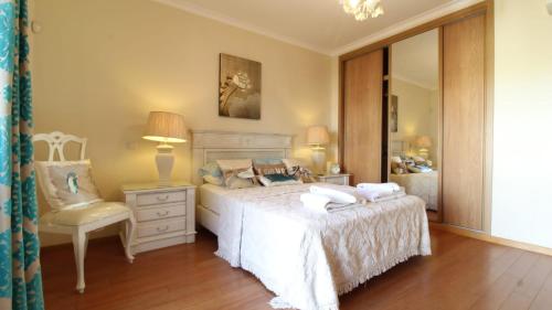 1 dormitorio con cama, silla y espejo en Casa Ana at Opomar by Cara Rentals, en Tavira