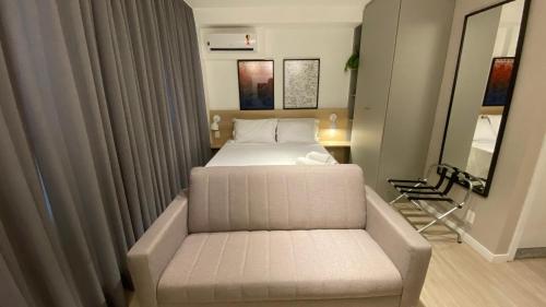 a bedroom with a bed and a couch and a mirror at Loft Grid Liberdade in São Paulo