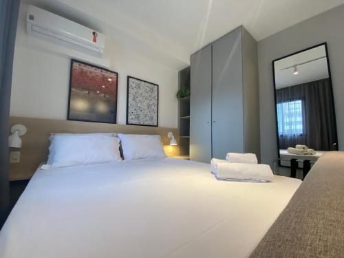 a bedroom with a large white bed and a desk at Loft Grid Liberdade in São Paulo