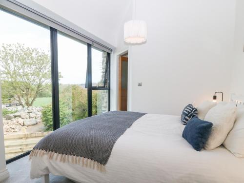a bedroom with a white bed with a large window at Pen-Y-Bryn in Llanfairpwllgwyngyll