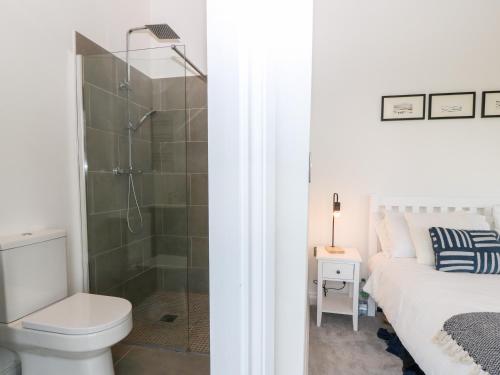 a bathroom with a shower and a toilet and a bed at Pen-Y-Bryn in Llanfairpwllgwyngyll