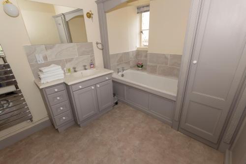 a bathroom with a tub and a sink and a mirror at Hayes Farm - 8 Houses in Gloucester