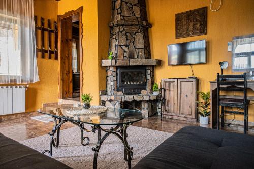 a living room with a table and a stone fireplace at Safari Village Velingrad in Velingrad
