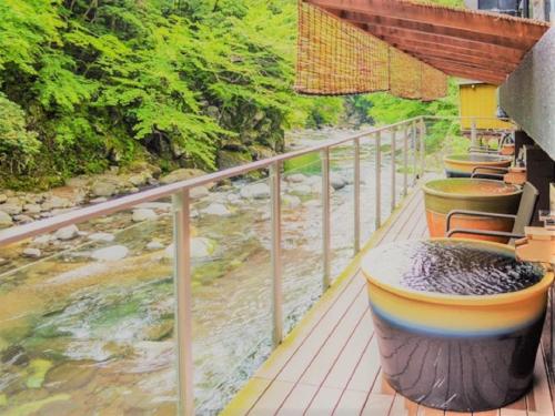 a balcony with tables and chairs next to a river at LiVEMAX RESORT Shizuoka Amagiyugashima in Izu