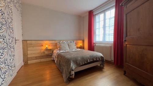 um quarto com uma cama e uma janela com cortinas vermelhas em Grenouilles et coquillages em Saint-Hilaire-Petitville