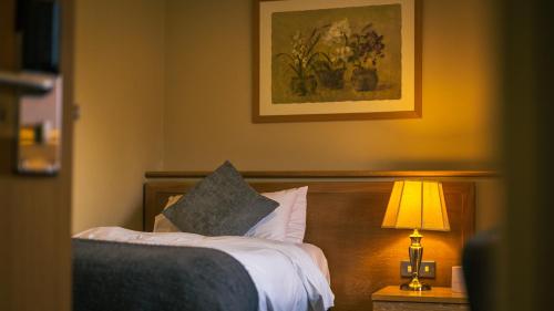 a bedroom with a bed with a lamp and a painting at The Old Mill in Coxhoe