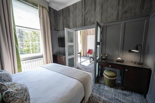 a bedroom with a bed and a desk and a window at Dunkeld House Hotel in Dunkeld