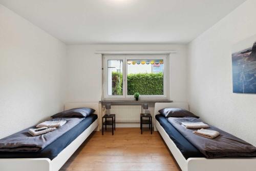 two beds in a room with a table and a window at FLEXAPART in Sargans by Fenus in Sargans