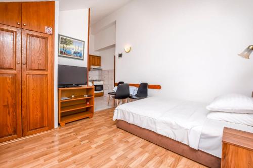 a bedroom with a bed and a desk and a television at Apartments Zdravko in Rogoznica
