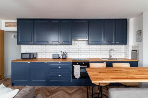 uma cozinha com armários azuis e uma mesa de madeira em Lovely 2- Bedroom Apartment with Stunning Sea Views em Worthing