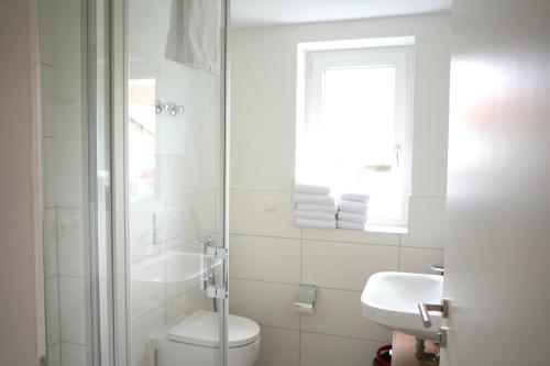 a white bathroom with a toilet and a sink at Exklusive Neubauwohnung mit wundervoller Aussicht nähe Europapark und Rulantica in Burgheim