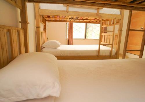 1 dormitorio con 2 camas blancas y ventana en Donde Ruka Hostal, en Santa Marta