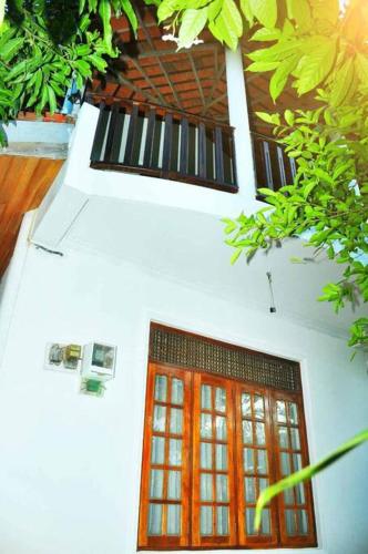a white building with a red door and some plants at Sunil Homestay in Tangalle