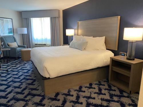 a hotel room with a large bed and a chair at The Inn on Maritime Bay, an Ascend Collection Hotel in Manitowoc