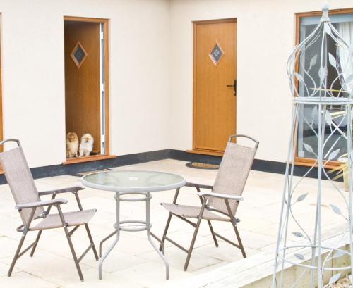 a glass table and chairs in a room with a dog at Mystique Barn in Bristol