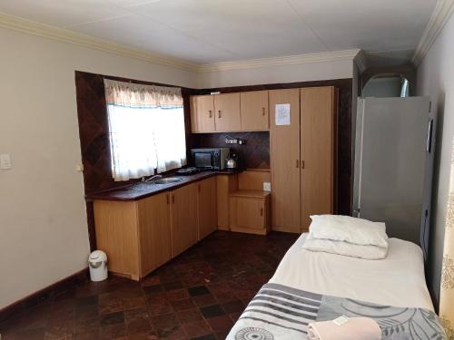 a small kitchen with a bed and a refrigerator at Insolam Accommodation in Mokopane