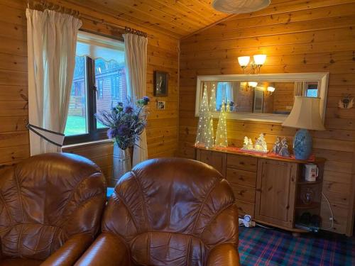 a living room with a leather chair and a mirror at Cozy Cabin with Stunning Loch Lomond Views in Rowardennan