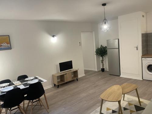 a living room with a table and chairs and a television at Hyper centre Saint-Gaudens appartement neuf in Saint-Gaudens