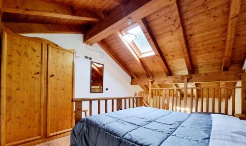 ein Schlafzimmer mit einem Bett in einem Zimmer mit Holzdecken in der Unterkunft Appartamento Adamello 10 in Pinzolo