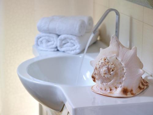 concha de mar sentada en la parte superior de un inodoro en el baño en Xenia Residence & Suites, en Pili