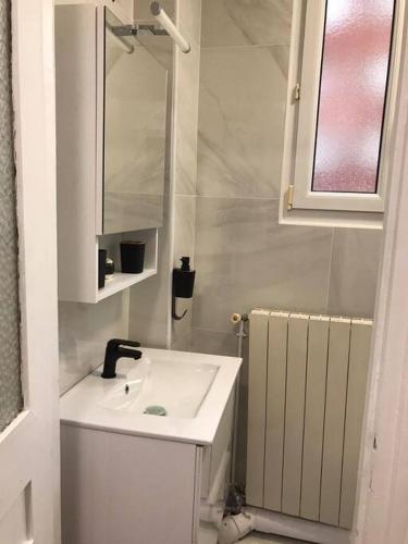 Charmant appartement cosy 2 pièces Paris 15e في باريس: حمام أبيض مع حوض ومرآة
