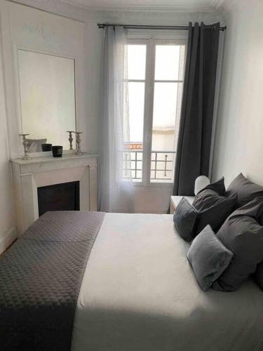 Schlafzimmer mit einem Bett, einem Kamin und einem Fenster in der Unterkunft Charmant appartement cosy 2 pièces Paris 15e in Paris