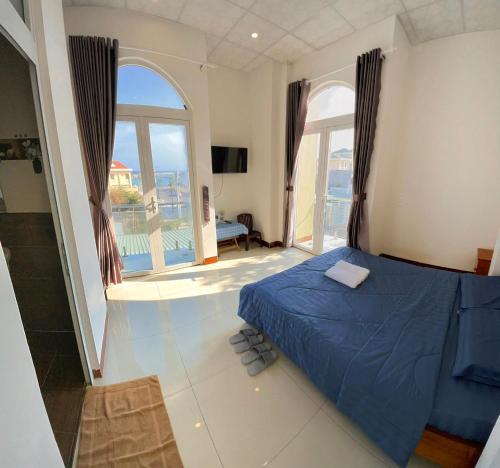 a bedroom with a blue bed and a large window at Homestay Hoài Tâm Phan Thiết in Ấp Sung Xuân