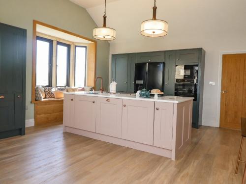 a large kitchen with white cabinets and a large island at Castleys in Skipton