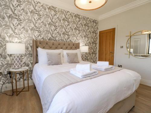 a bedroom with a large white bed with a patterned wall at Castleys in Skipton